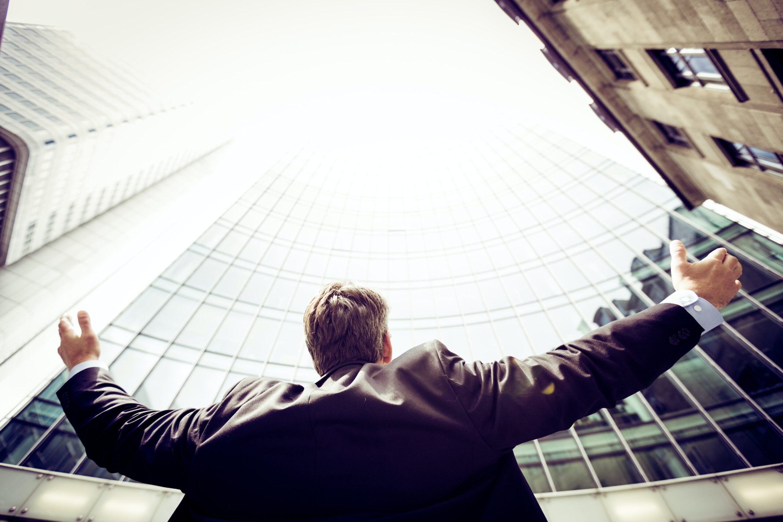 Career low-angle photography of man in the middle of buidligns