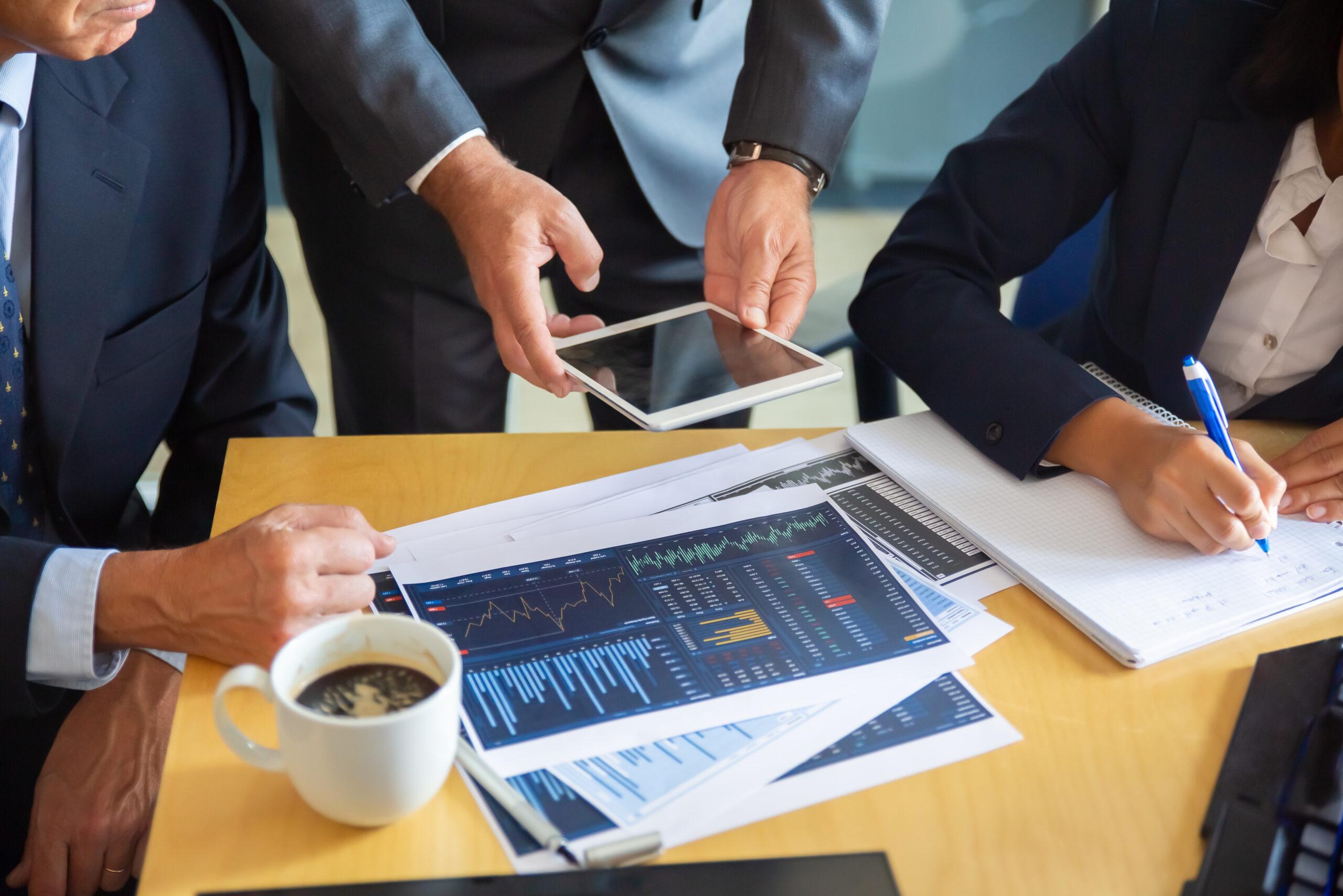 Unrecognizable business partners working with statistic charts Unrecognizable business partners working with statistic charts. Businessman holding tablet. Professional content businesswoman making notes for statistics. Communication and partnership concept